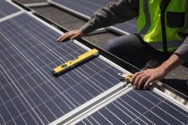 Section médiane du travailleur masculin travaillant sur des panneaux solaires à la station solaire — Photo de stock
