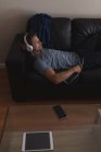 Человек слушает музыку на наушниках в гостиной дома — стоковое фото