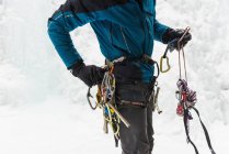 Mid section of male rock climber wearing harness near rocky mountain during winter — Stock Photo