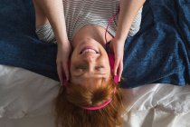 Frau mit Kopfhörer hört zu Hause Musik im Schlafzimmer — Stockfoto
