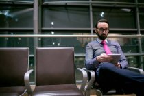 Geschäftsmann nutzt digitales Tablet im Wartebereich am Flughafen — Stockfoto