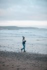Frau geht in der Dämmerung am Strand spazieren — Stockfoto
