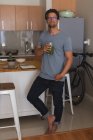 Homem tomando um copo de suco na cozinha em casa — Fotografia de Stock