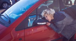 Jovem mulher olhando no espelho retrovisor do carro — Fotografia de Stock