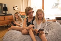 Fratelli che utilizzano il telefono cellulare e tablet digitale in soggiorno a casa — Foto stock