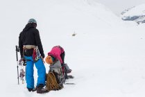 Casal de pé com mochila e arnês em uma montanha coberta de neve durante o inverno — Fotografia de Stock