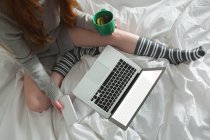 Partial view of woman using laptop in bedroom at home — Stock Photo