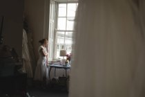 Bride in white dress looking through the window at boutique — Stock Photo