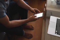 Uomo che utilizza il telefono cellulare in soggiorno a casa — Foto stock