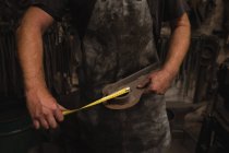 Schmied vermessen Metall mit Maßband in Werkstatt — Stockfoto