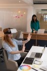 Designer gráfico feminino usando fone de ouvido de realidade virtual no escritório — Fotografia de Stock