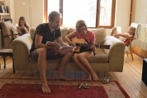 Father helping her daughter to play guitar in living room — Stock Photo