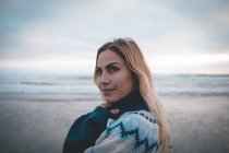 Задумчивая женщина, стоящая на пляже в сумерках — стоковое фото