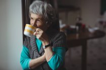 Удумлива старша жінка має каву вдома — стокове фото
