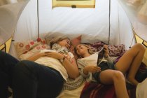 Mother and daughter using digital tablet in tent at home — Stock Photo
