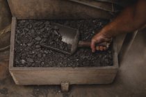 Forgeron enlever les charbons de la boîte dans l'atelier — Photo de stock