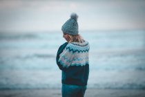 Задумчивая женщина, стоящая на пляже в сумерках — стоковое фото