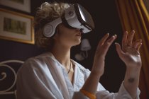 Женщина с гарнитурой виртуальной реальности в спальне дома — стоковое фото
