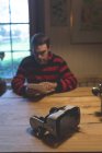 Auriculares de realidad virtual en la mesa mientras el hombre utiliza la tableta digital en casa - foto de stock