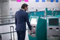 Бизнесмен пользуется автоматом по продаже авиабилетов в аэропорту — стоковое фото