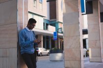 Бизнесмен, пользующийся мобильным телефоном вне офиса в солнечный день — стоковое фото