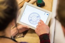 Carpinteiros masculinos e femininos olhando para o plano em tablet digital na oficina — Fotografia de Stock