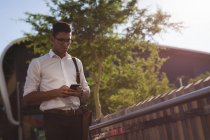 Uomo d'affari che utilizza il telefono cellulare fuori in una giornata di sole — Foto stock