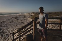 Surfista maschio in piedi con tavola da surf vicino alla spiaggia in una giornata di sole — Foto stock