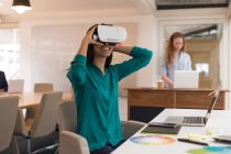 Designer gráfico feminino usando fone de ouvido de realidade virtual no escritório — Fotografia de Stock
