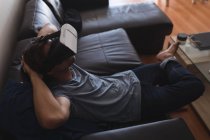 Homme utilisant casque de réalité virtuelle dans le salon à la maison — Photo de stock