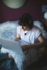 Женщина с ноутбуком с гарнитурой в спальне на дому — стоковое фото