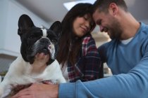 Romantic couple playing with their pet dog in kitchen at home — Stock Photo