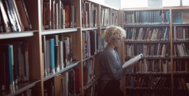 Молодая женщина, читающая книгу в библиотеке — стоковое фото