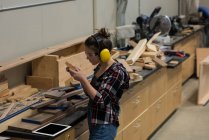 Женщина-плотник осматривает кусок дерева в мастерской — стоковое фото