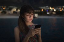 Frau benutzt Handy in der Abenddämmerung am Strand — Stockfoto