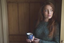Задумчивая женщина пьет зеленый чай дома — стоковое фото