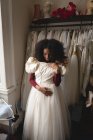 Mulher africana selecionando vestido de noiva de cabides de roupas na boutique — Fotografia de Stock