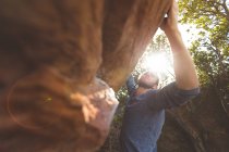 Чоловічий пішохід сходження на скелясту гору в сільській місцевості на сонячний день — стокове фото