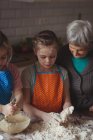 Бабушка и внучки готовят кексы на кухне дома — стоковое фото