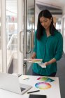 Designer gráfico feminino segurando cartões de cor no escritório — Fotografia de Stock