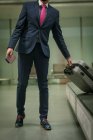 Geschäftsmann nimmt Gepäck vom Gepäckband am Flughafen — Stockfoto