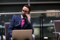 Бізнесмен розмовляє по мобільному телефону в зоні очікування в аеропорту — стокове фото