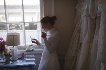 Молода наречена у весільній сукні читає записку в бутіку — стокове фото