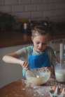 Маленькая девочка готовит печенье на кухне дома — стоковое фото