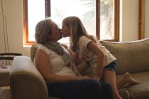 Mãe e filha se beijando na sala de estar em casa — Fotografia de Stock