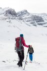 Vista trasera de la pareja caminando sobre una montaña cubierta de nieve durante el invierno - foto de stock