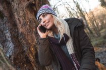 Jovem mulher falando no celular na floresta — Fotografia de Stock