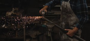 Schmied schleift Metallstange mit Schleifmaschine in Werkstatt — Stockfoto