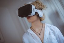 Jeune femme utilisant casque de réalité virtuelle à la maison — Photo de stock