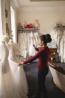 Mixed-race woman taking photo of wedding dress on mobile phone in boutique — Stock Photo